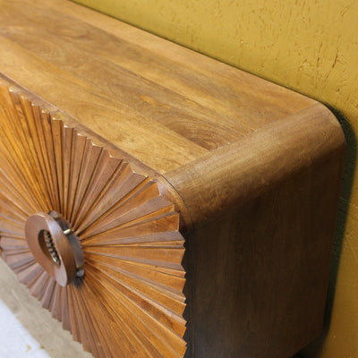 Side view of wooden sideboard with detailed circular carved door design