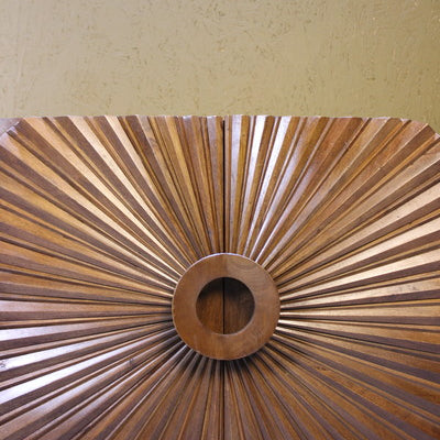 Close-up of wooden sideboard door with radial carved design and circular centre