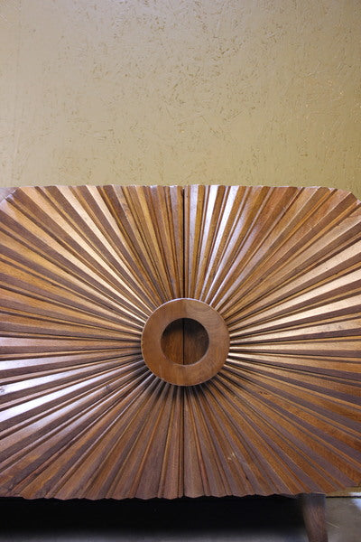 Close-up of wooden sideboard door with radial carved design and circular centre