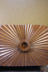 Close-up of wooden sideboard door with radial carved design and circular centre