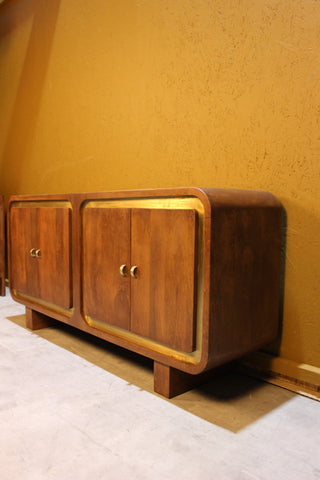 Wooden sideboard with square design and gold trim set against yellow wall