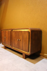 Wooden sideboard with square design and gold trim set against yellow wall