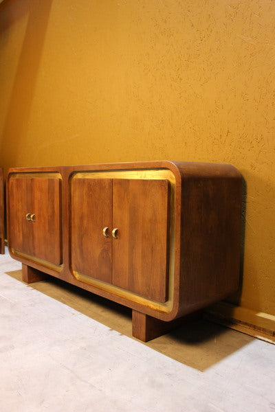 Wooden sideboard with square design and gold trim set against yellow wall