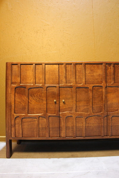 Wooden sideboard with intricate square and rectangle carvings and metal knobs