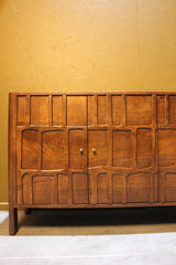 Wooden sideboard with intricate square and rectangle carvings and metal knobs