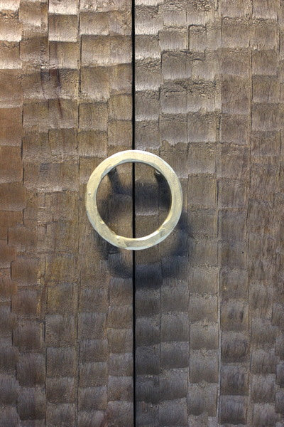Circular metal handle on textured wooden doors with chiseled pattern
