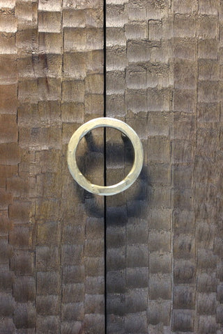Circular metal handle on textured wooden doors with chiseled pattern