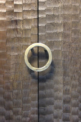 Circular metal handle on textured wooden doors with chiseled pattern