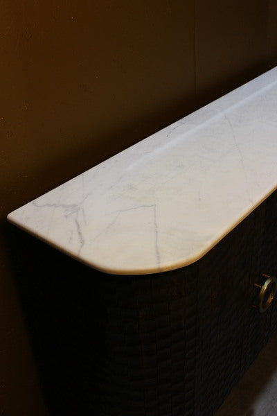 Rounded white marble top on dark textured wooden sideboard