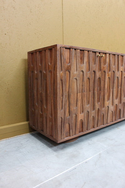 Brown sideboard with carved retro pattern on wooden doors and brass handles