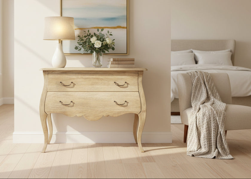 Curved wooden chest with two drawers, lamp, flowers and books on top