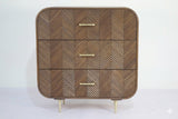 Sonar chest of 3 drawers in dark mango wood with layered chevron drawer fronts and gold-tone handles and legs, front view on plain background