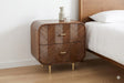 Sonar 2 drawer bedside in dark mango wood with layered chevron drawer fronts, gold-tone handles and legs, beside a bed
