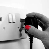 A hand plugging in an Atmos electric fire into a wall socket.