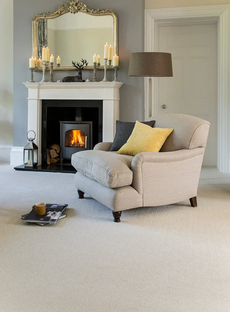 Light grey armchair with yellow and grey cushions in a cozy living room with fireplace.