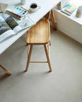 Light beige carpet in a home office with a wooden stool and open magazine on a white desk.