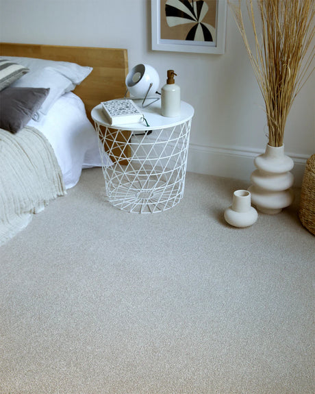 Soft beige carpet in a bedroom, styled with a white wire side table and decorative items.