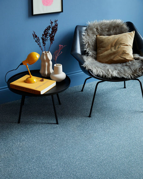 Blue carpet with a soft, textured surface in a modern room featuring a black chair and side table.