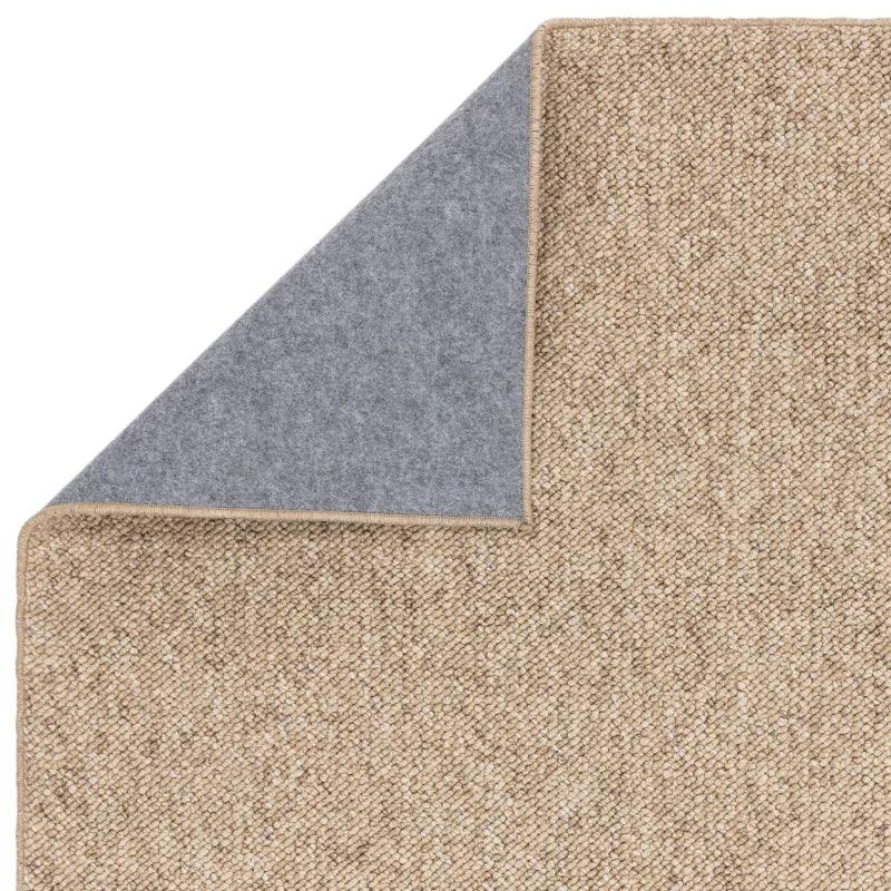Beige woven rug with grey felt backing, close-up of corner detail