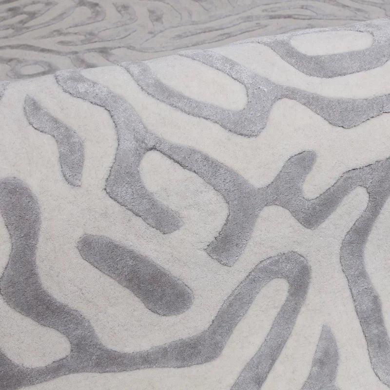 Modern area rug with raised grey abstract pattern on cream background, close-up view