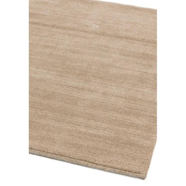 Beige area rug with subtle texture and finished edges viewed from an angle