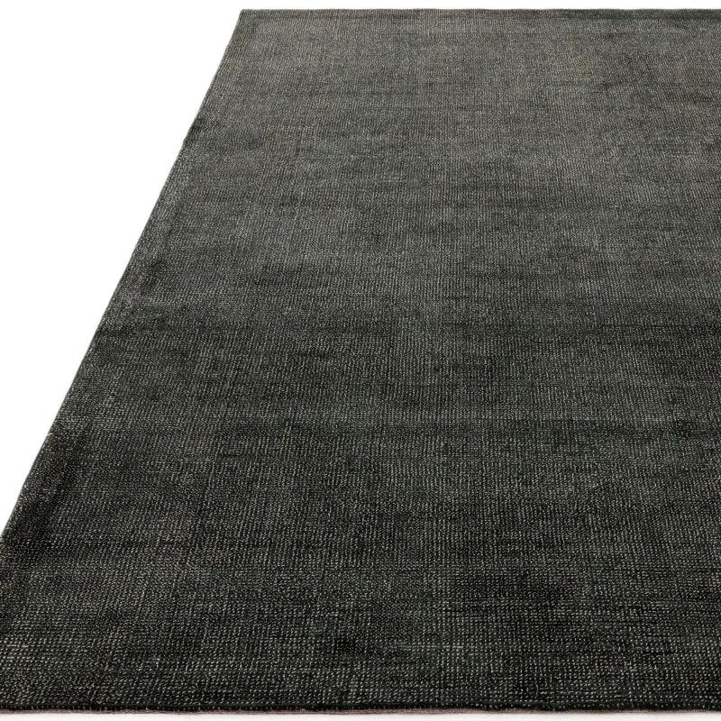 Charcoal woven area rug with subtle texture and finished edges, shown from corner angle
