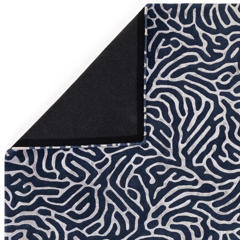 Blue and white abstract patterned rug corner with contrasting solid black reverse