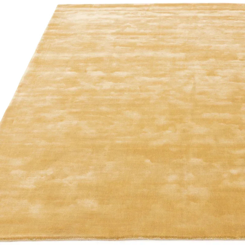 Rectangular gold area rug with soft texture on white background
