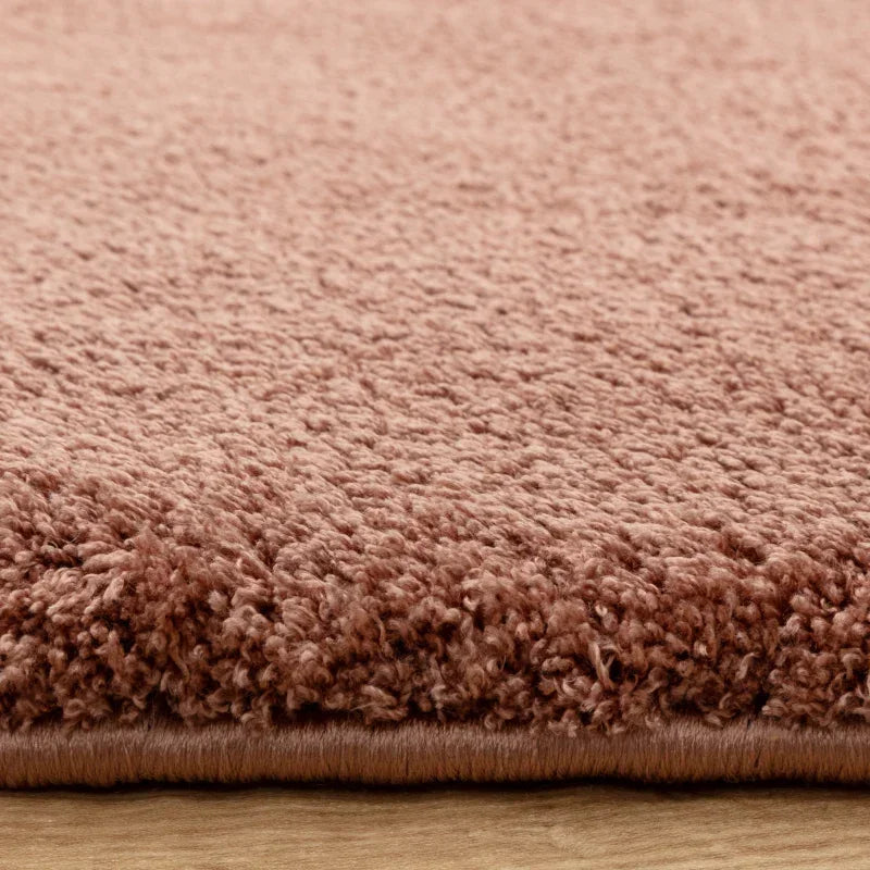 Close view of soft pink textured rug on wooden floor
