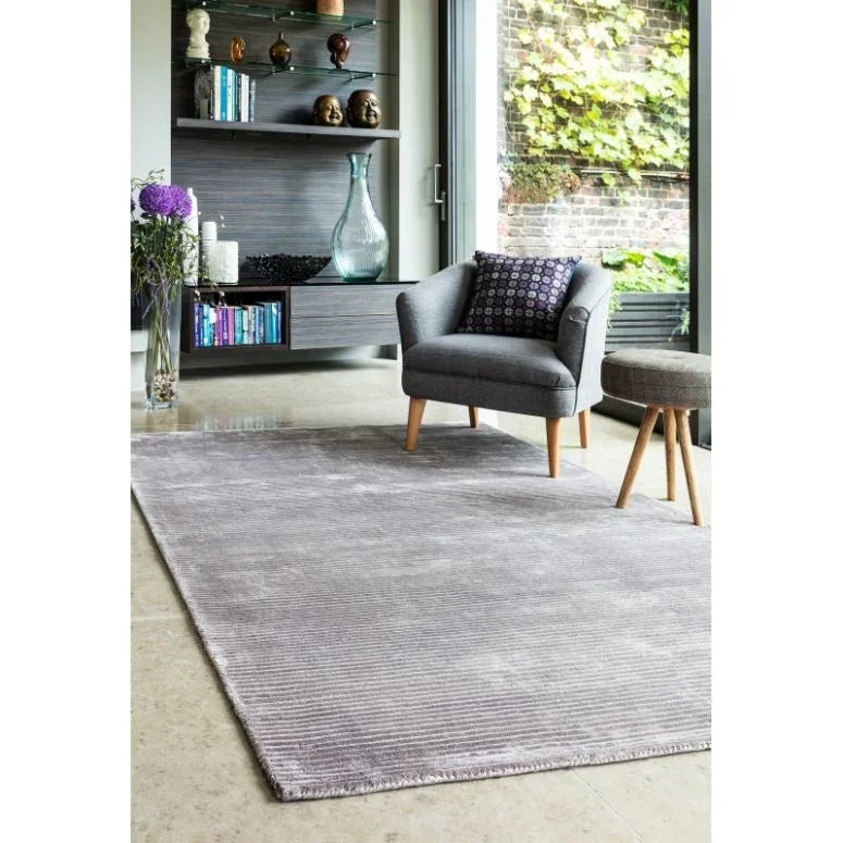 Grey area rug in modern living room with grey armchair and open shelving