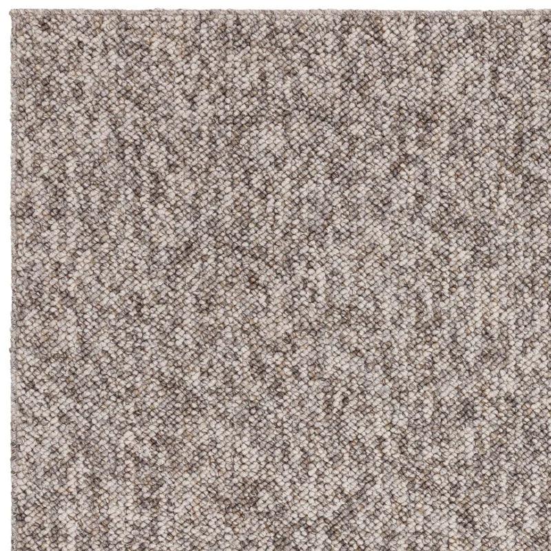 Close-up of textured beige woven rug corner with neutral tones and looped pile detail