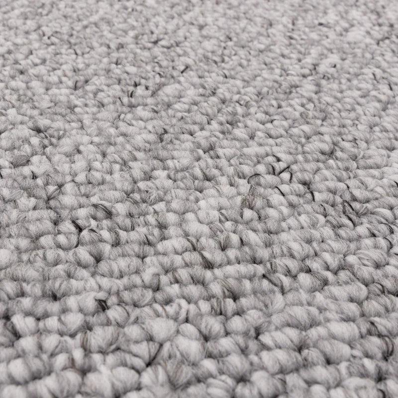 Close-up of textured grey wool rug surface with looped pile design
