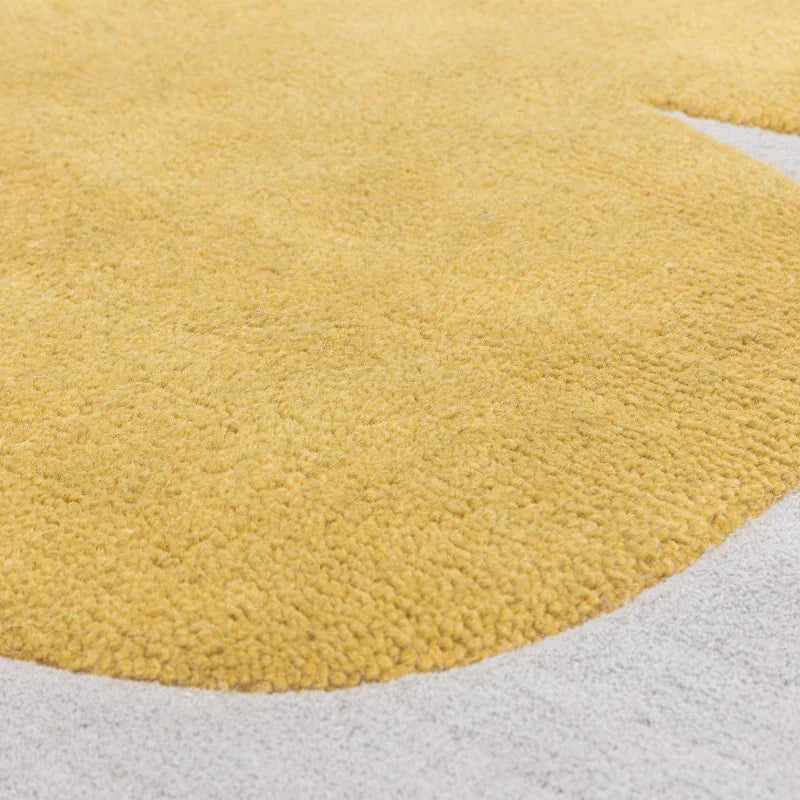 Close up of yellow tufted rug on light grey carpet