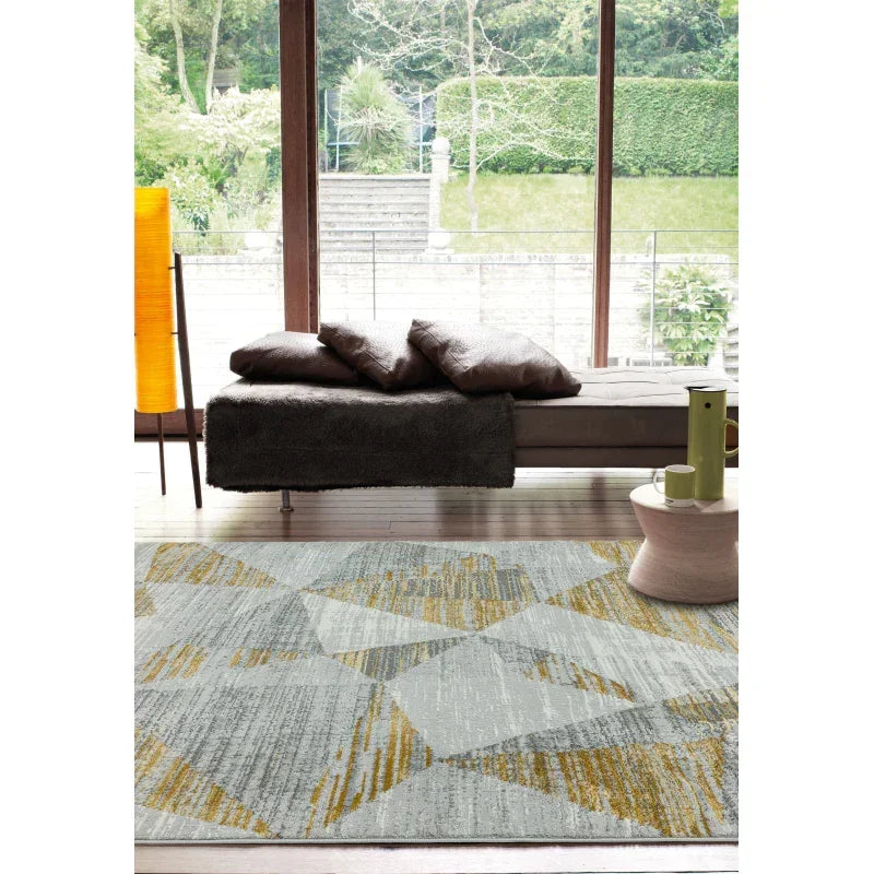 Geometric patterned area rug in grey and yellow under modern sofa in bright living room