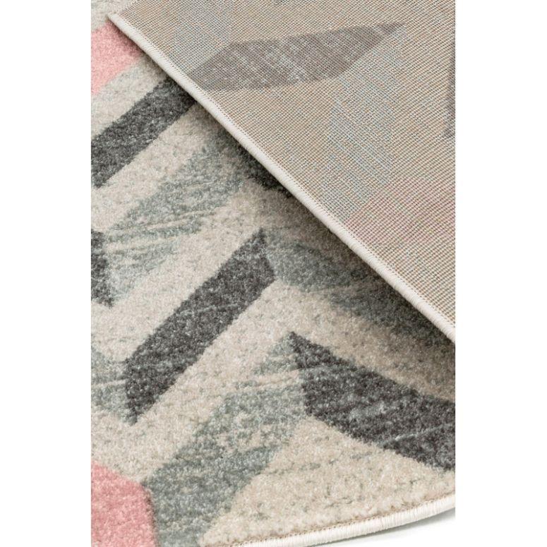 Geometric patterned rug in grey, cream, and pink with close view of corner and backing