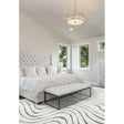 Modern bedroom with tufted bed, cream bench, and wavy patterned rug