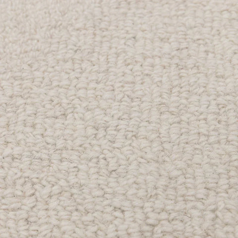 Closeup of cream textured carpet fabric with looped wool surface