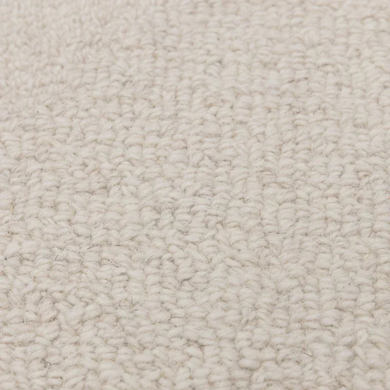 Closeup of cream textured carpet fabric with looped wool surface