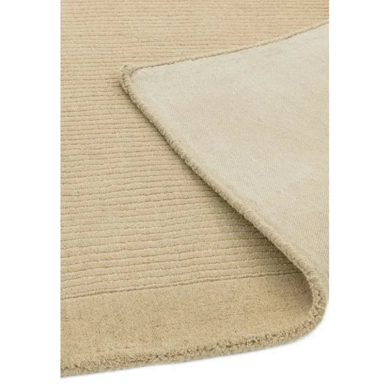 Beige textured area rug with folded corner showing backing and ribbed surface design