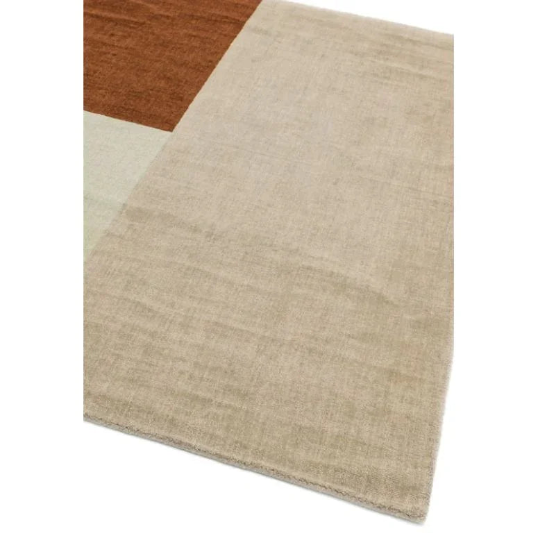 Modern area rug with beige, brown, and light grey geometric blocks, close corner view
