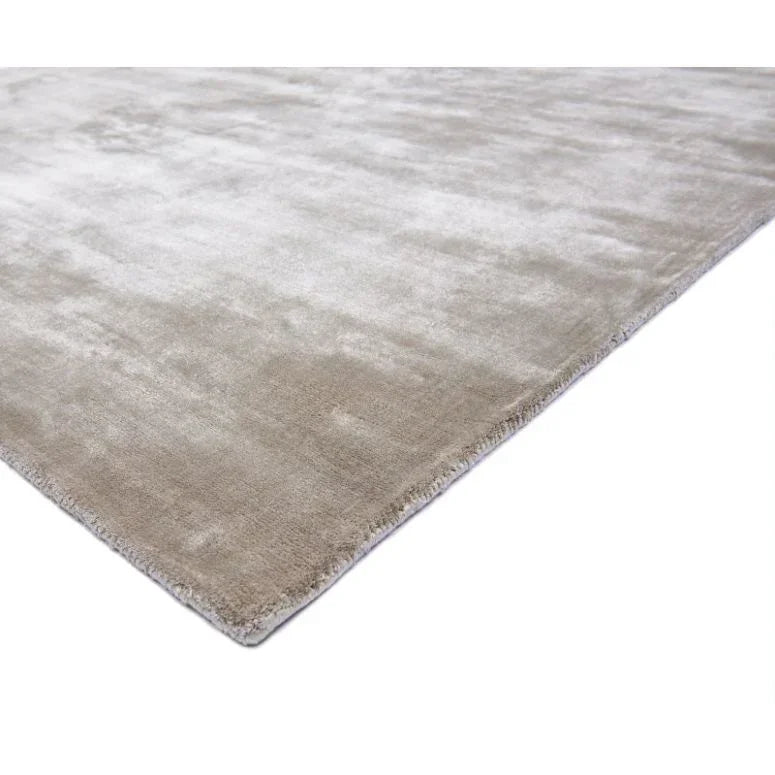 Beige area rug with soft texture and low pile, close corner view on white background