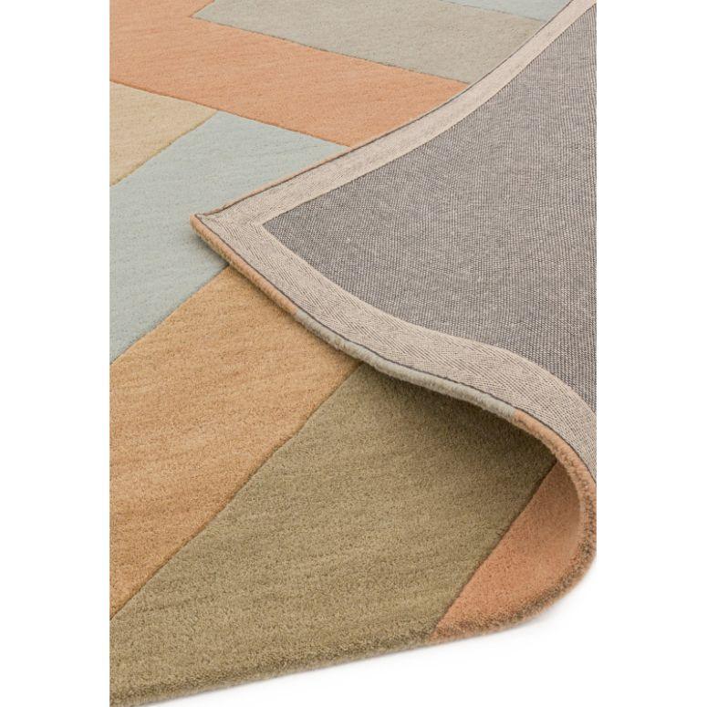 Geometric area rug with folded corner showing multicolour blocks and textured backing