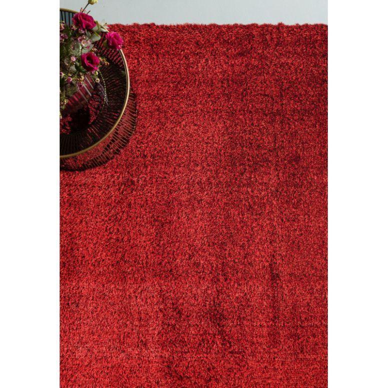 Red shaggy rug with textured pile and metal side table with pink flowers