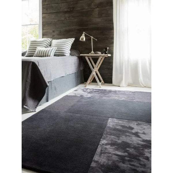 Grey geometric area rug on bedroom floor beside modern wooden side table
