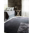 Grey geometric area rug on bedroom floor beside modern wooden side table