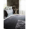 Grey geometric area rug on bedroom floor beside modern wooden side table