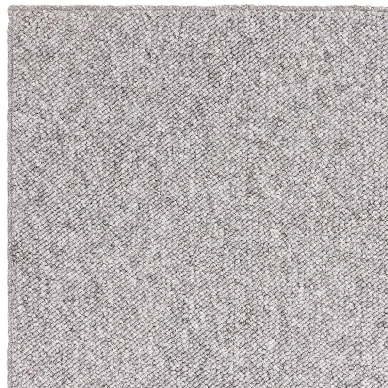 Close-up of light grey textured rug corner with woven fabric detail