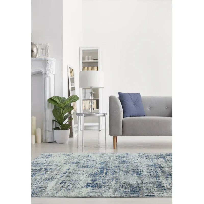 Blue patterned area rug in modern living room with grey sofa and glass side table