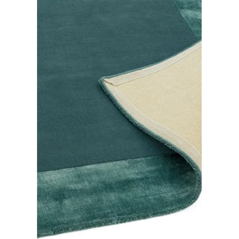 Teal area rug with soft texture, corner flipped to show beige backing