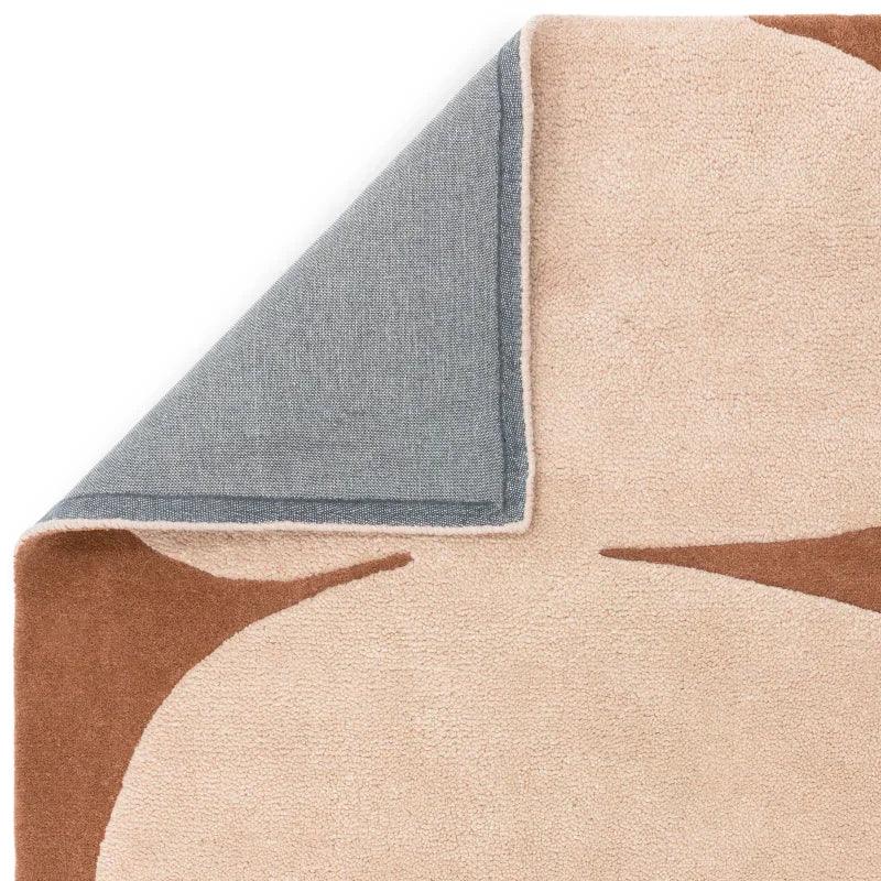 Beige and brown abstract rug with corner flipped to show grey backing
